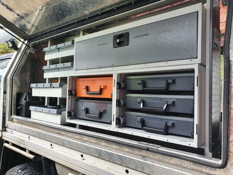 Storage system with drawers and compartments on a vehicle's open cargo area.